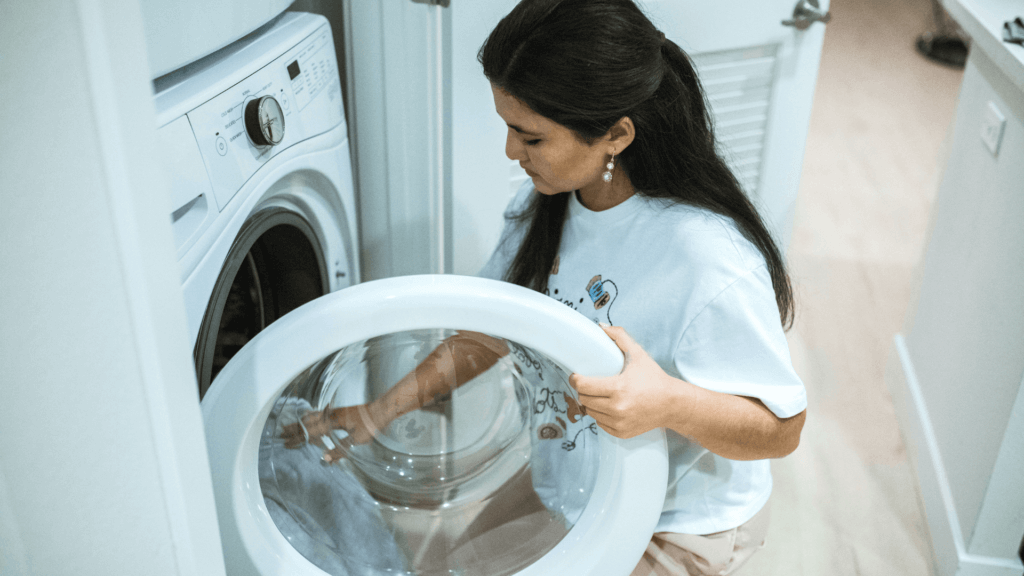 Sieviete ievieto apģērbu veļas mašīnā